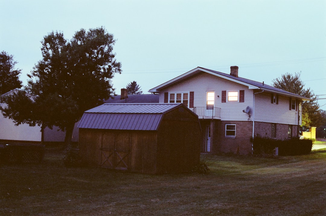 brown wooden house near green tree during daytime