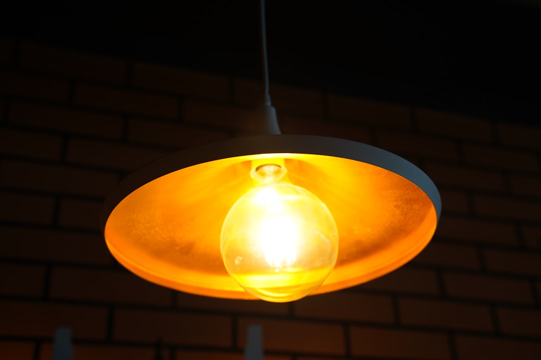 a yellow light hanging from a brick wall