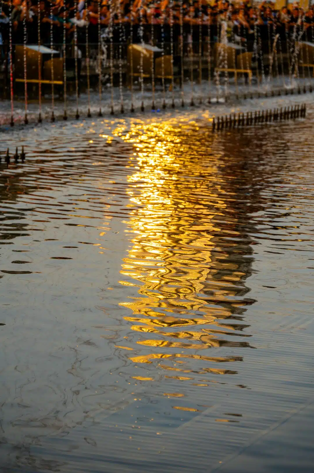 Water reflects golden light from a fountain.